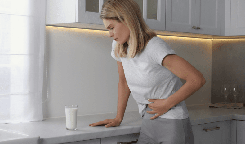 Objawy nietolerancji laktozy - osoba, która ściska się za brzuch