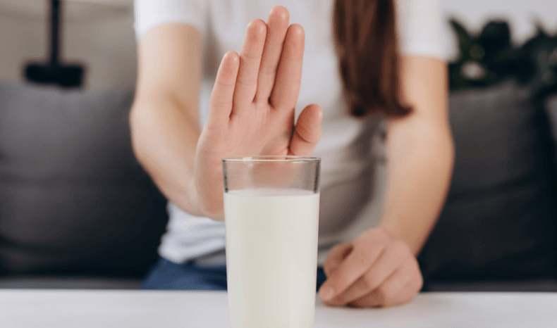 Osoba z nietolerancją laktozy – zdjęcie osoby, np. Odsuwającej szklankę z mlekiem